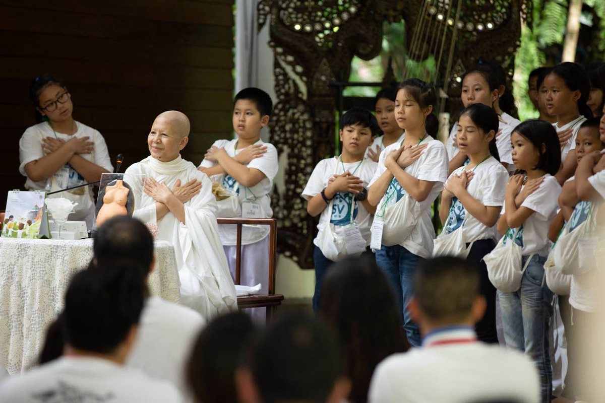 Ven. Mae Chee Sansanee Sthirasuta with ISV Club youth, hands crossed over their hearts together